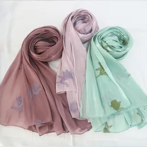 Detailed view of embroidered island silk scarves showcasing delicate floral patterns and texture.