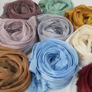 Close-up detail of rolled island silk embroidered scarves showing rich color variety and soft texture.