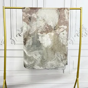 Detailed view of a marble print modal cotton scarf hanging neatly on a gold display stand.