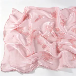 Close-up of pink crinkled embroidered scarf showcasing delicate floral details and shiny edges.