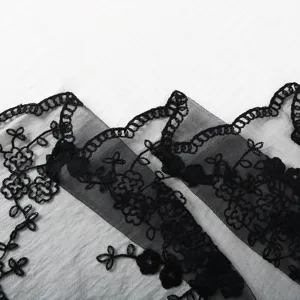 Detailed black lace fabric featuring intricate embroidered floral mesh texture and scalloped trim.