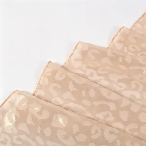 Close-up of gold-foil leopard chiffon scarf detail, showing smooth drape and soft texture.