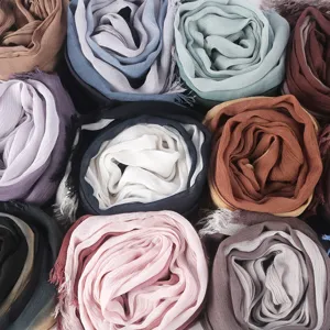 Primo piano di foulard stropicciati arrotolati in cotone viscosa con bordi a frange colorate.