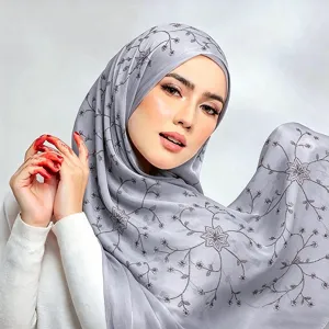 Primo piano dettagliato dell'hijab in seta grigia con delicati ricami floreali e shimmer.