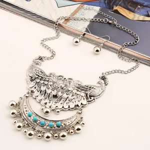 Close-up detail of vintage silver-tone peacock necklace and earrings set with turquoise beads.