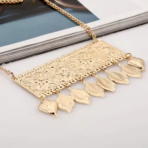Collana con ciondolo a foglia in metallo dorato intarsiato, dettaglio gioiello stile bohémien.
