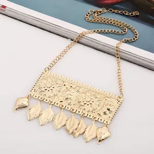 Dettaglio in primo piano della collana bavetta con foglia intagliata in metallo dorato.
