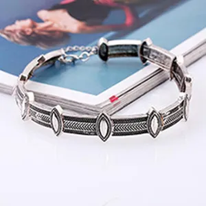 Detailed close-up of a vintage silver metallic geometric bracelet with intricate carved links.