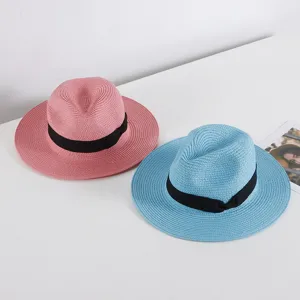 Vista detallada de sombreros de paja de verano rosa y azul con cintas negras para protección.
