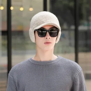 Close-up detail shot of a warm winter knitted hat with earflaps and brim worn by a male model.