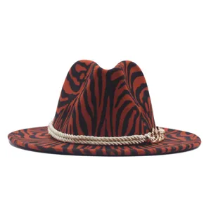 Primo piano dettaglio del cappello fedora in lana motivo zebrato arancione nero con catena.