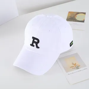 Dettaglio di berretto da baseball bianco con lettera R ricamata nera ed etichetta laterale.