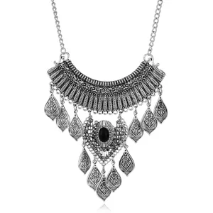 Detailed close-up of vintage silver necklace with black stone and decorative leaf charms.