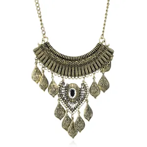 Close-up of vintage gold-toned statement bib necklace with intricate leaf engravings and crystals.