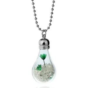 Detailed close-up shot of glass bulb pendant necklace with green dried flowers and clear beads.