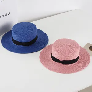 Close up detail of stylish flat top straw hats with black ribbon, perfect for summer beach.