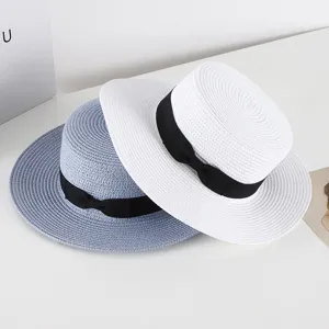 Detailed view of summer flat top straw hats with black ribbon bow, elegant sun protection beach hat.
