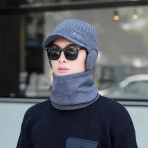 Nahaufnahme der grauen gefütterten Strickmütze und des passenden Schlauchschals im Freien.