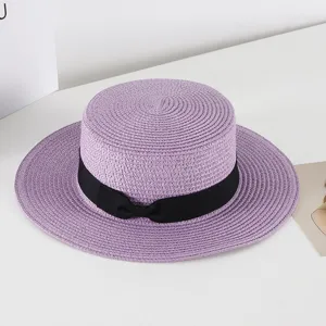 Purple straw boater hat with black ribbon bow detail, flat top sun hat for summer beach travel.