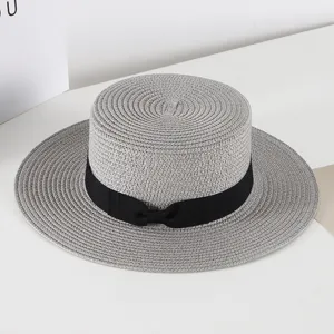 Detailed view of women flat top straw hat with black ribbon bow, vintage summer sun hat.