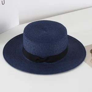 Navy blue straw hat detail, flat top wide brim design with black bow ribbon for summer.
