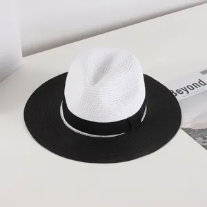 Close-up details of a chic two-tone straw hat featuring a white crown and wide black brim.