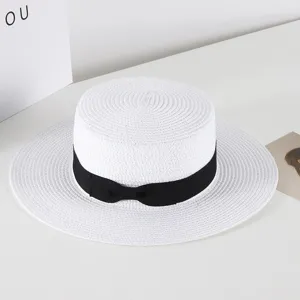 Details of the white straw flat-top hat with black bow ribbon, summer sun protection.