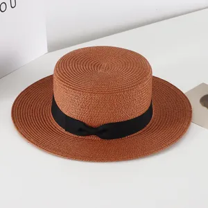 Classic brown flat top straw hat with black ribbon bow, stylish summer sun protection beach hat.