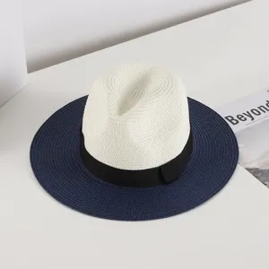 Detail view of a chic women's straw fedora hat with white crown, black bow band, and navy brim.