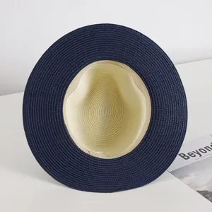 Close-up detail of the stylish straw hat featuring a wide blue brim and beige crown.