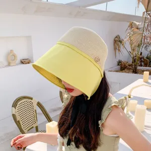 Stylish color-blocked sun hat with wide brim, straw crown, and chic black ribbon tie.