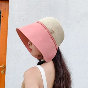 Detail view of women's color-block sun hat with wide pink brim and metallic button decoration.