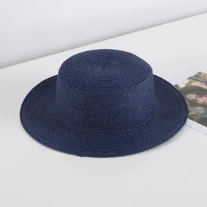 Detailed close-up view of dark blue flat top straw hat with woven texture for summer beach.