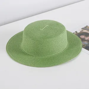 Detailed view of the stylish green flat top straw hat, perfect summer beach sun protection.