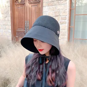 Close-up detail of the black wide brim sun hat, featuring side rhinestone decor and ribbon tie.