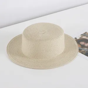 Close-up detail of the stylish beige flat top straw hat with neat woven texture for summer.