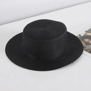 Black flat top straw hat for women, ideal for summer beach travel and sun protection.