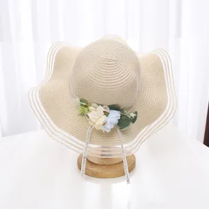 Gros-plan d'un chapeau de paille à large bord avec décoration florale, bordure en filet et rubans.