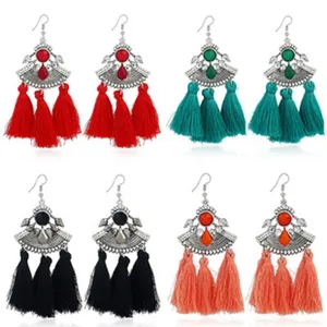 Nahaufnahme von böhmischen Vintage-Quastenohrringen mit Metallfächeranhängern und Fransen.