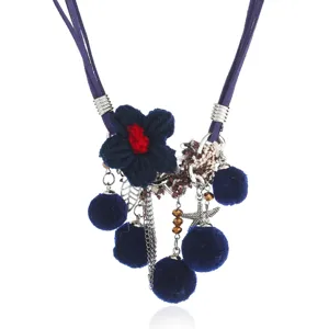 Blue braided flower and pom-pom tassel necklace detail shot, bohemian style fashion jewelry.