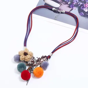 Multi-strand suede cord necklace featuring colorful pom-poms and knitted flower pendants.