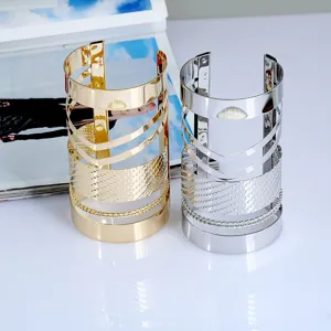 Primo piano dettagliato di ampi bracciali rigidi in metallo con design punk traforato.