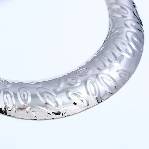 Nahaufnahme Detail der breiten silbernen Metallhalskette mit abstraktem Prägemuster-Design.