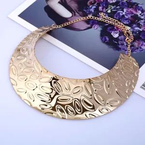 Exaggerated punk style metallic bib necklace close-up, bold gold textured collar detail.