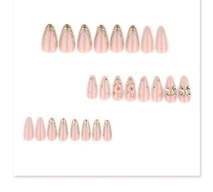 Vue détaillée de faux ongles avec des bouts français dorés, des strass et des nœuds mignons.