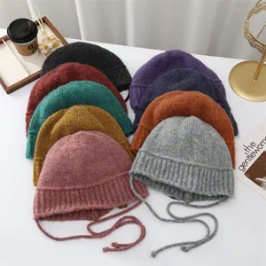Cappelli a secchiello in maglia multicolore con cordini, berretti invernali caldi vista dettagli.