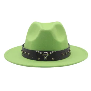 Détail de chapeau fedora vert avec bande en cuir noir, badge crâne de taureau et rivets.