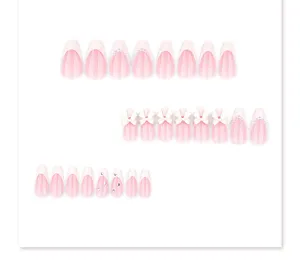Close-up detail of pink press-on nail set featuring elegant pearl and bow decorations.