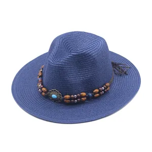 Nahaufnahme des blauen Strohhutes mit stilvollem Holzperlenband für den Sommerurlaub.