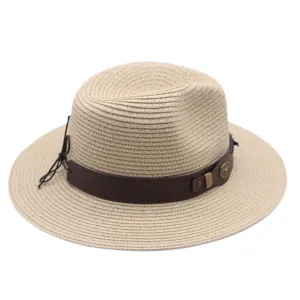 Gros plan d'un chapeau de paille beige avec bande en cuir marron et badge taureau.